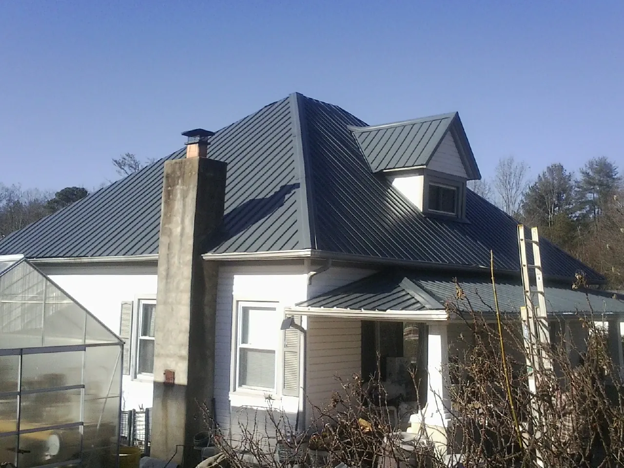 Dark blue standing seam metal roof on a white farmhouse with dormer — Slate & Tile Roof Repair by Roofing Brothers in Derry