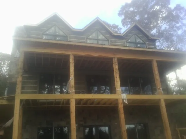 Dormers and porch framing on a large log home under construction — Roof Coating work by our crew in Derry