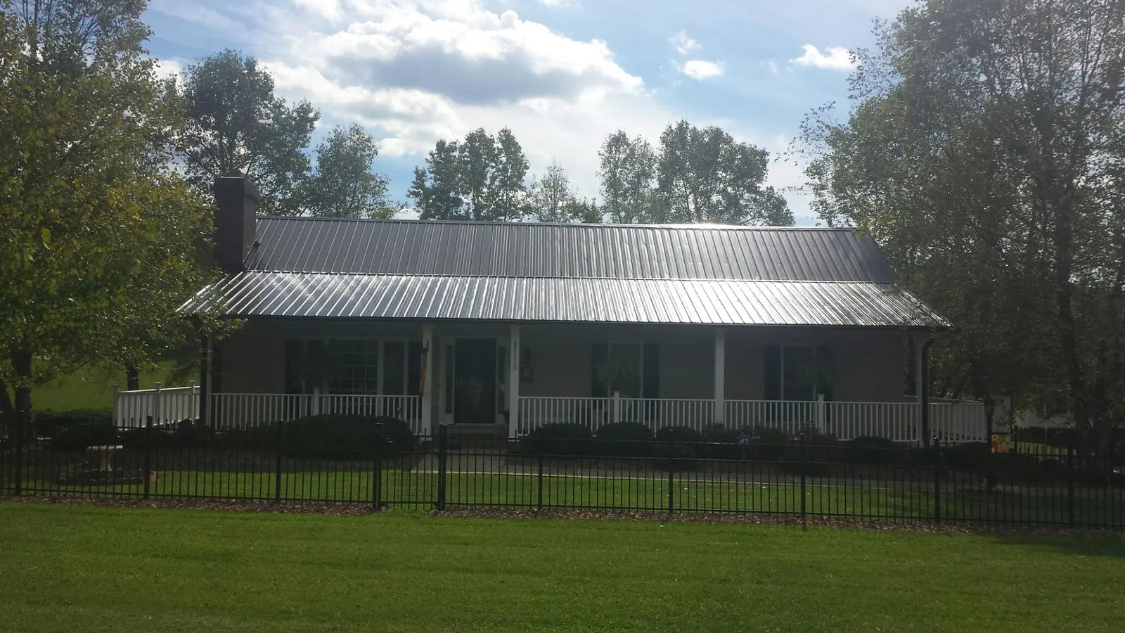 Gray metal roof on a brick ranch with a full width front porch — Gutter Guard Installation work by our crew in Derry