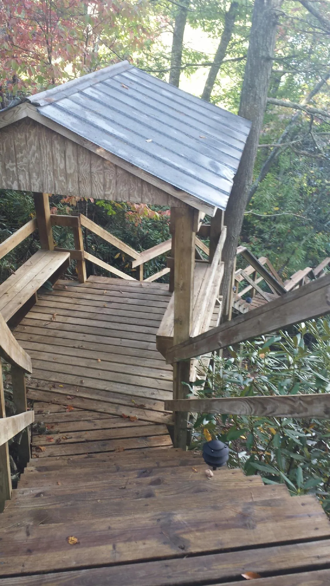 Metal roofed shelter over wooden steps on a wooded walkway — Skylight Repair & Installation work by our crew in Derry