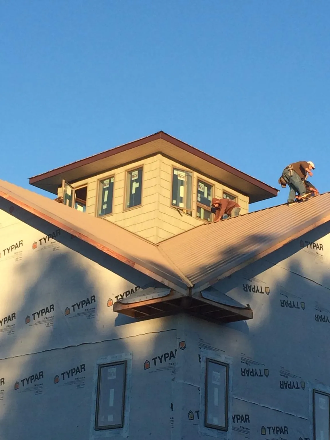 Roofers working around a rooftop cupola on a new metal roof at sunset — Roof Waterproofing in Derry by Roofing Brothers